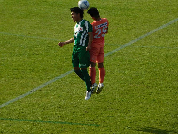 空中でハイボールを競り合う両軍選手