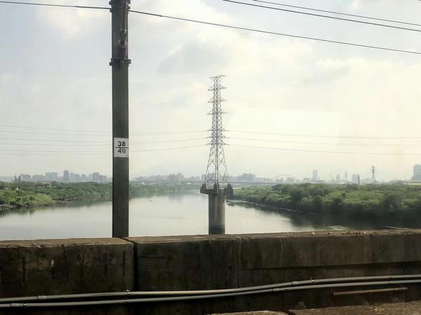 車窓から見た河川の中の高圧鉄塔