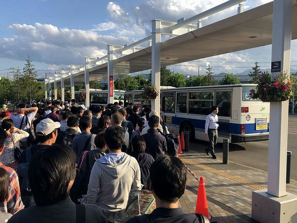 二十四軒駅行きの無料送迎バスに乗り込む人々