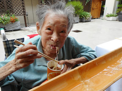 入居者が流しそうめんを食べて笑顔をこぼす