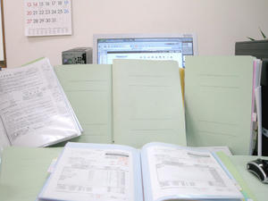 資料に囲まれた机（誇張気味）