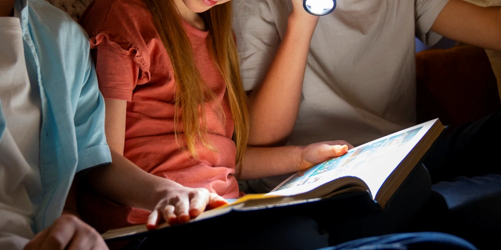 懐中電灯で本を読む子