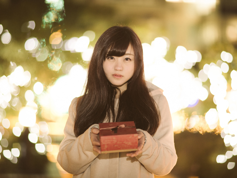 街の夜景を背にプレゼントを渡す女性